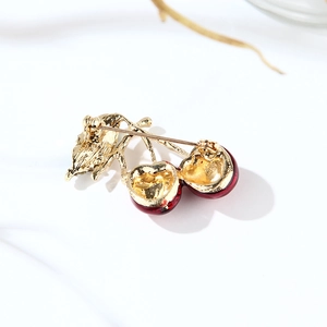 Minimalist red cherry enamel brooch with golden metal leaves and branches on white background