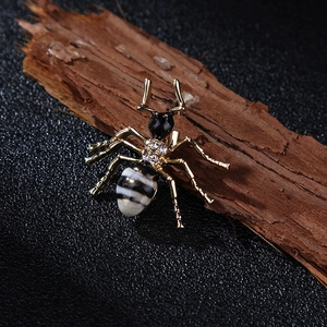 Détail d'une broche fourmi avec strass et émail noir et blanc sur écorce de bois