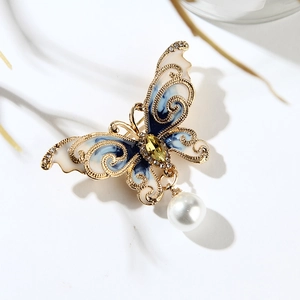 Détail d'une broche papillon en émail bleu marbré avec une élégante perle pendante