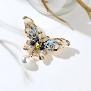 Détail d'une broche papillon en émail bleu avec perle pendante et zircone jaune
