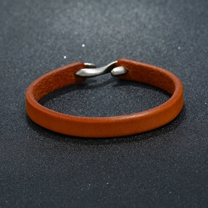 Close-up of brown leather bracelet with a unique metal S-hook clasp and textured detail