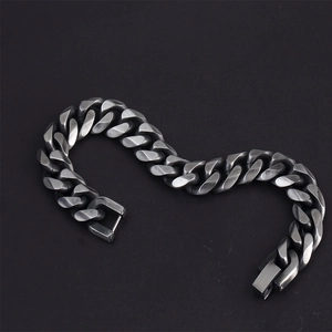 Macro view of gunmetal Cuban link bracelet with brushed matte finish on dark background