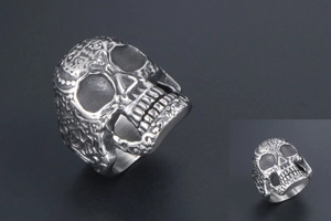 Macro shot of vintage skull ring showing intricate floral engravings and dark oxidized finish