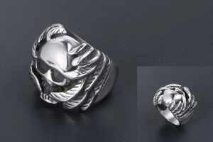 Detailed view of silver gothic skull ring with intricate wing texture on the metal band