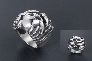 Close-up of gothic silver skull ring with detailed feather wings and punk metal texture