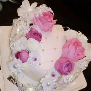 Detailed view of artificial pink cake with floral roses, lace patterns and gold beads