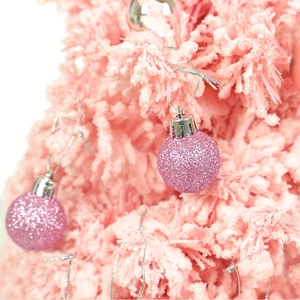 Pink glitter Christmas ball ornament hanging on a pink flocked tree branch for decor