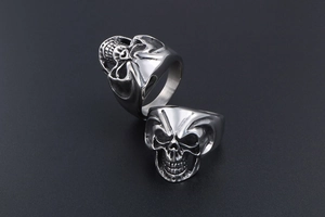 Detailed macro view of two stainless steel skull rings showing front and side profile