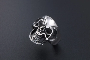 Macro shot of silver titanium steel skull ring showing detailed carving and polished finish