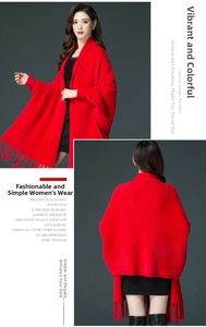Detail of red knit shawl with batwing sleeves and long fringe tassels at the hem