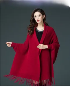 Close-up of red knit poncho featuring long fringe tassels and warm fuzzy texture
