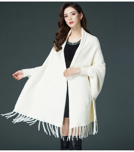 Detailed view of a white knitted shawl cardigan featuring elegant tassel trim and plush texture
