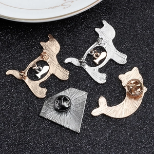 Vista posteriore di quattro spille in metallo a forma di gatto e lisca in oro e argento su nero