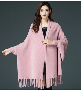 Detail of pink knitted poncho with elegant fringe hem and soft faux mink fur texture