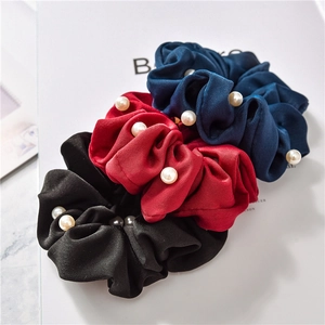 Close-up of premium satin scrunchies with white pearl embellishments in three colors
