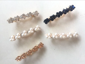 Detail showing elegant pearl and crystal hair clips in various colors on metal base