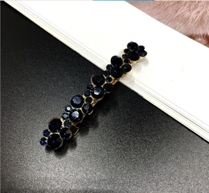 Detail view of vintage dark blue faceted crystals on a gold alloy hair clip