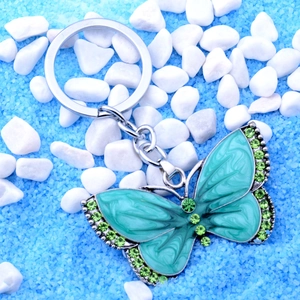 Macro shot of silver butterfly keychain with teal enamel and green rhinestones
