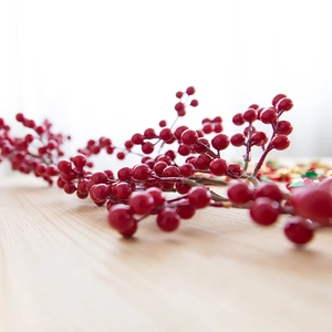 Lush artificial red berry branch for Christmas decoration on a rustic wooden table