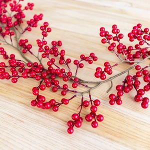 Lush red Christmas berry garlands and branches on a minimalist wooden table background
