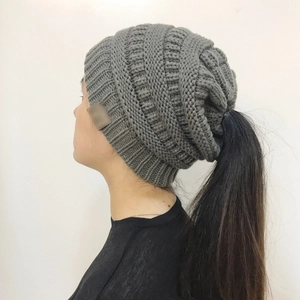 Detail of grey knitted ponytail beanie showing the thick knit texture and side logo tag