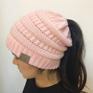Detail view of pink cable knit ponytail beanie showing the top opening and texture