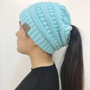 Detail view of light blue cable knit ponytail beanie showing the top opening and elastic texture