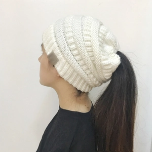 Side view of white knit ponytail beanie showing clear ribbed texture and opening