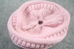 Close-up of pink knitted beanie detail showing soft texture and ponytail hole design
