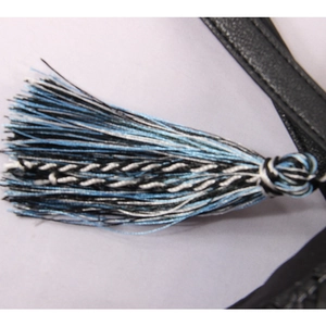 Detail of colorful woven tassel charm and leather strap on a straw beach bag