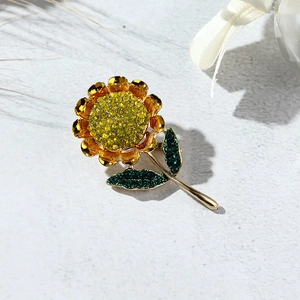 Detail of sunflower brooch featuring yellow and green crystals with golden metal finish