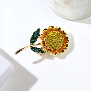 Macro shot of sunflower brooch with yellow and green crystals on gold-plated petals