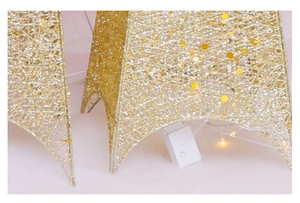 Détail de l'étoile dorée scintillante avec lumières LED chaudes et tissage en maille