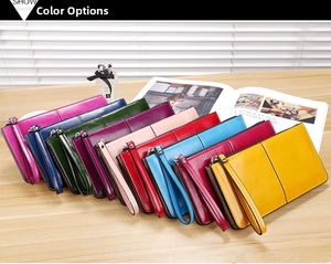 Detail view of multi-color long leather wallets with wrist straps on a wooden surface