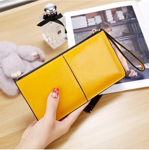 Close-up of yellow leather long wallet with zipper and wrist strap in lifestyle scene