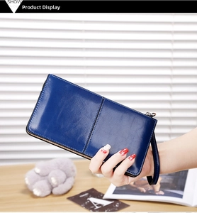Detail of blue waxed leather long wallet with wrist strap held by a model