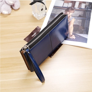 Detail of dark blue long leather wallet with silver zipper and wristlet on wooden desk