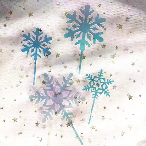 Detailed view of four iridescent snowflake acrylic cake toppers on a glitter tulle background