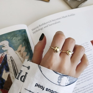 Artistic shot of golden geometric rings on fingers with a minimalist art book background