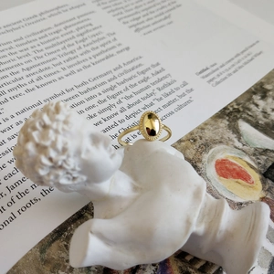 Artistic close-up of a gold oval signet ring on a plaster bust over a vintage book