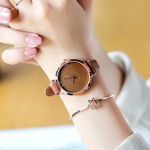 Detail of rose gold ladies watch with brown leather strap and star pattern bracelet