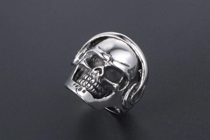 Detailed close-up of a silver punk skull ring featuring side headphone carvings and metal texture