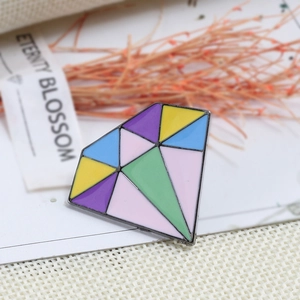 Dettaglio della spilla in smalto a forma di rombo con motivi geometrici colorati e bordi neri