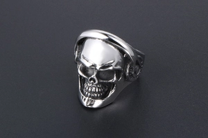 Close-up of punk skull ring with headphones in vintage silver finish on grey surface