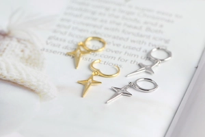 Macro shot of silver and gold S925 sterling silver star drop earrings on an open book