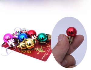 Size comparison showing 2cm mini colorful Christmas ball ornaments on a credit card