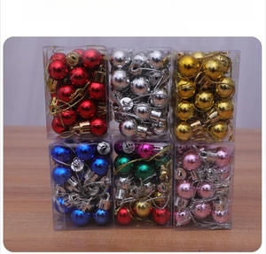 Assorted colorful mini Christmas balls in clear PVC boxes on a wooden surface
