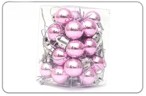 Close-up of shiny pink Christmas ornaments with silver caps in a transparent box