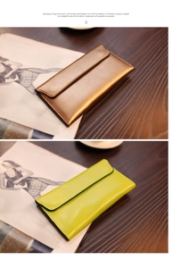 Detailansicht langer Leder-Umschlagbörsen in Bronze und Neongelb auf einem Holztisch
