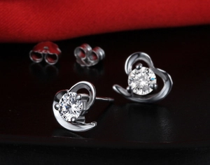 Macro shot of silver heart swirl earrings with clear sparkling round gemstones